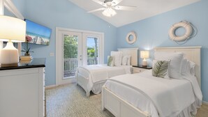A bedroom with two beds, a ceiling fan, and a view of the outdoors through a door. - CASA DE VINO ~ Amazing Price for  Charming Townhouse with Pool & Tiki! (Key West)