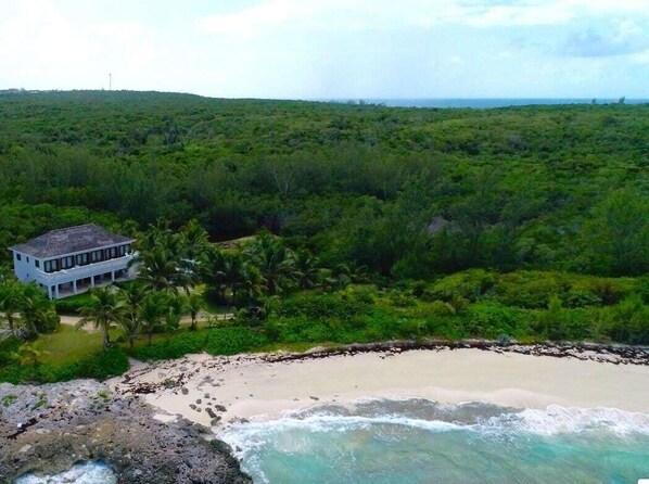 A coastal property with a large house surrounded by dense greenery and a beach. - Private Beachfront Home w/Pool, Solar, Banks Rd, Walk to Restaurants (Governors Harbour)