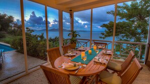 A wooden table set for dining with a view of the sea and mountains.