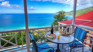 A balcony with a table and chairs, overlooking a scenic ocean view.