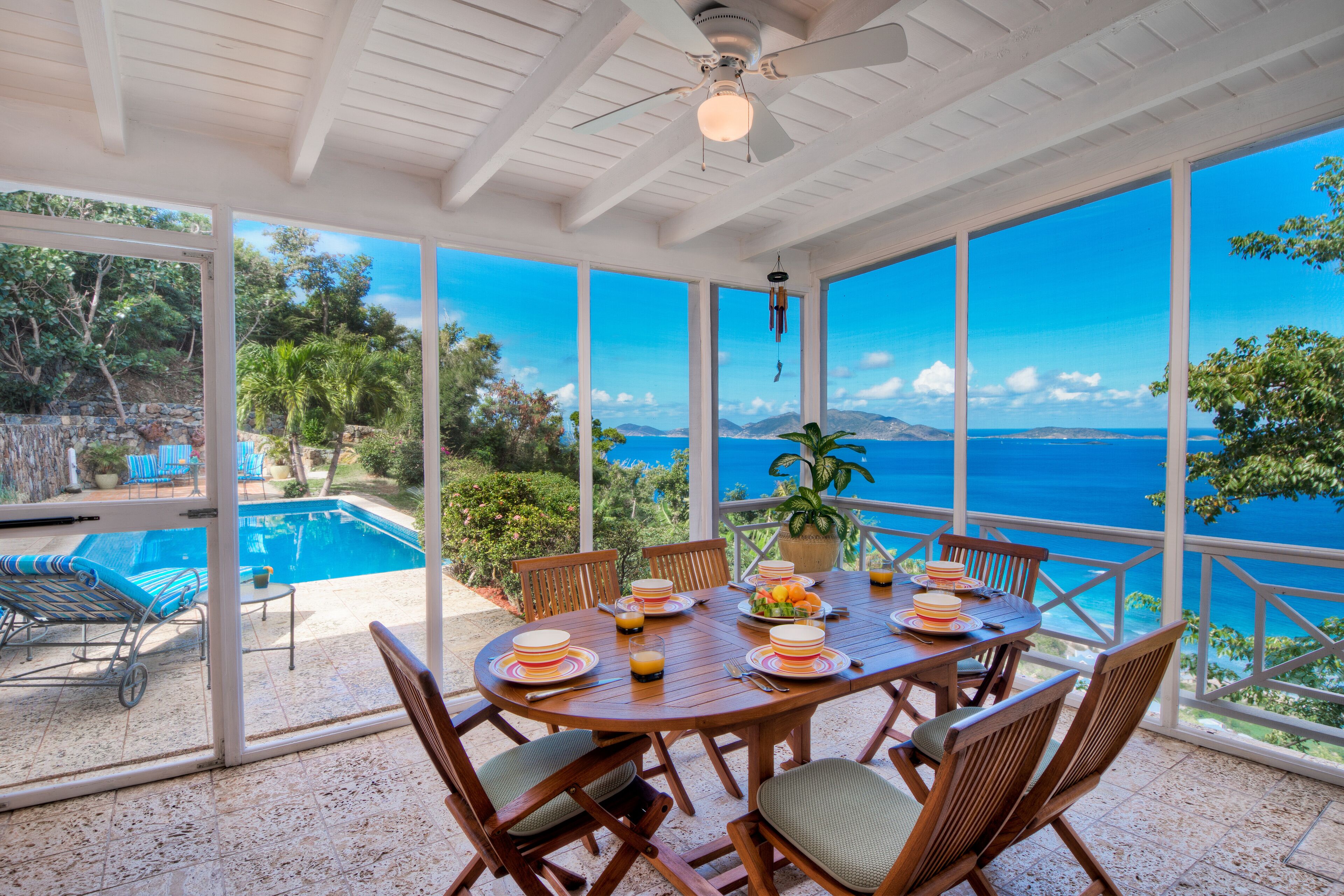 Un espace extérieur abrité, aménagé pour les repas, avec vue sur la mer, une piscine et une terrasse dotée de chaises longues.