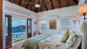 A bedroom with a bed, a view of the sea, and a balcony.