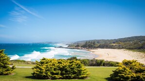 A coastal landscape with a beach, ocean waves, and green vegetation. - 120 Ocean Parade Dalmeny (Dalmeny)