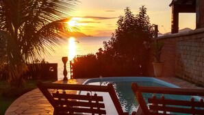 A poolside area with a sunset view, benches, and a brick wall. - House in front of the sea with a beautiful sunrise, deck for good fishing With WI- (Mangaratiba)