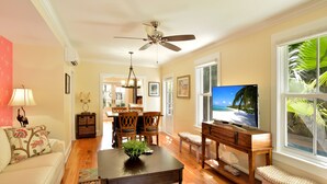 A spacious living room with a wooden coffee table, a sofa, and a television. - STARS ~ 4 bedroom, 2 Bath Condo, Shared Heated Pool, Downtown Location! (Key West)