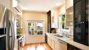 A kitchen with stainless steel appliances, a dishwasher, and a window overlooking a garden. - STARS ~ 4 bedroom, 2 Bath Condo, Shared Heated Pool, Downtown Location! (Key West)