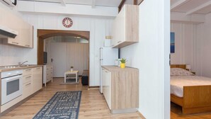 Un appartement moderne et compact comprenant une cuisine, un petit coin repas et une chambre.