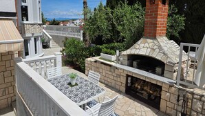 Un espace patio doté d’un four extérieur en pierre, de mobilier d’extérieur blanc et offrant une vue sur le paysage environnant.