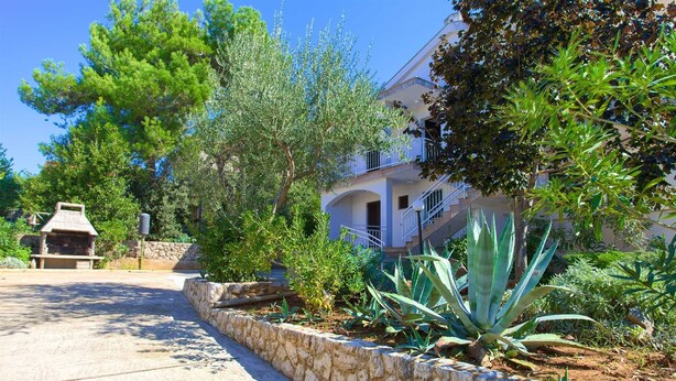 A stone pathway leading to a building with a barbecue area and lush greenery. - Apartment Vlatko 2 with Terrace (Krk)