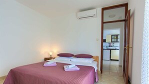 A bedroom with a bed, pillows, a nightstand, and an air conditioning unit. - Apartment Vlatko 2 with Terrace (Krk)