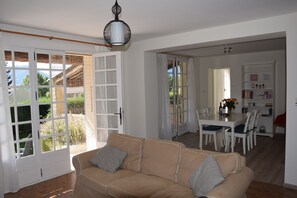 A spacious living area with a beige sofa, a dining table with chairs, and a kitchen area in the background. - Superb holiday house in the natural beauty of the Gorges de Verdon (Castellane)