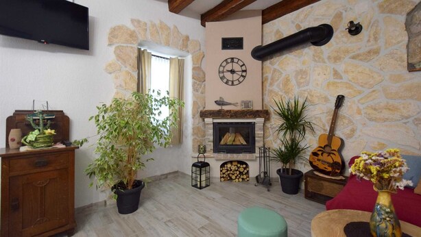 Ein gemütliches Wohnzimmer mit Kamin aus Stein, Holzboden und einem an der Wand befestigten Flachbildfernseher.
