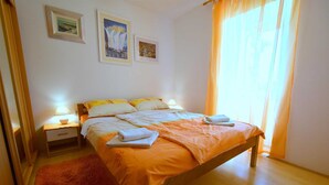 Ein Schlafzimmer mit einem Bett, Nachttischen, einem roten Teppich und zwei gerahmten Bildern an der Wand.