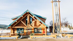 A log cabin with a triangular roof and a ski lift nearby.