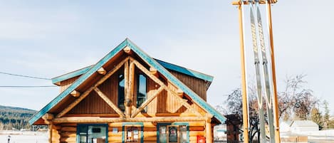 A log cabin with a triangular roof and a ski lift nearby.