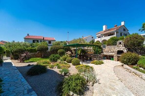 A courtyard with stone pathways, a stone oven, and a covered seating area. - Apartment Juranic with spacious Terrace (Krk)