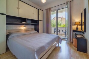 A bedroom with a bed, a desk, a chair, and a view of the outside. - Apartment Juranic with spacious Terrace (Krk)