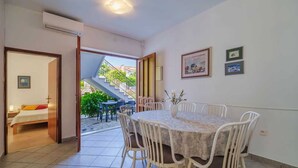 A dining area with a round table and chairs, a small vase with flowers, and a staircase leading outside. - Apartment Juranic with spacious Terrace (Krk)