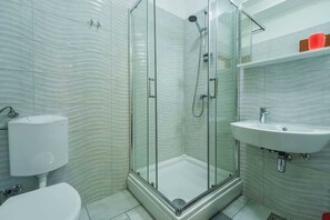 A modern bathroom with a glass-enclosed shower, a white sink, and a toilet. - Apartment Juranic with spacious Terrace (Krk)