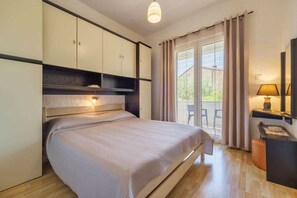A bedroom with a bed, a desk, a chair, and a window with curtains. - Apartment Juranic with spacious Terrace (Krk)