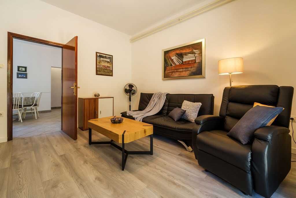 Uma sala de estar com sofá, poltrona reclinável, mesa de centro de madeira e abajur.