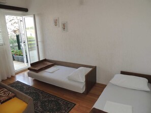 A bedroom with a single bed, a sofa, and a small table. There is a sliding glass door leading to a balcony with plants. - Apartment Dragica 2 on the ground floor (Malinska)