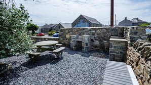 A stone wall with a wooden bench and picnic table, surrounded by gravel.