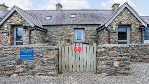 A stone building with a wooden gate, a sign indicating private parking, and a small window.