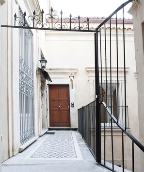 A narrow alleyway leading to a wooden door with a metal gate above. - SICILY EXCLUSIVE CHARMING APARTMENT IN THE HEART OF MODICA'S HISTORICAL CENTER! (Modica)