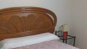 Una cama bien tendida con una colcha estampada y dos toallas enrolladas.