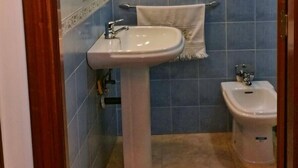 Un baño con lavamanos pedestal, un bidé y un espejo.