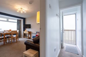A living room with a sofa, a coffee table, and a dining area with chairs and a table. - Bay View: A two bed, pet-friendly holiday apartment in Rhosneigr (Rhosneigr)