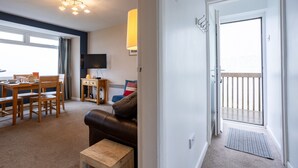 A living room with a sofa, a coffee table, a TV, and a dining area with a table and chairs.