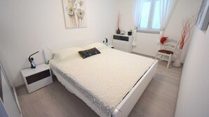 Een slaapkamer met een bed, nachtkastje en een stoel.
