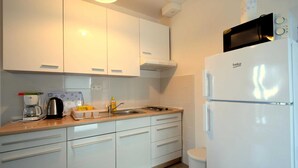 A modern kitchen with white cabinets, a built-in oven, a microwave, and a sink. - Apartment Cindrić 2 on the 2nd floor (Gabonjin)