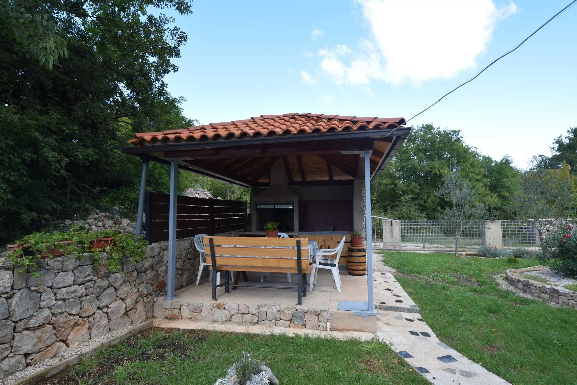 Un espacio al aire libre cubierto con pared de piedra, banco de madera y techo de baldosas.