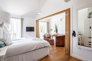 A hotel room with a bed, a desk, a chair, a TV, and a mirror.