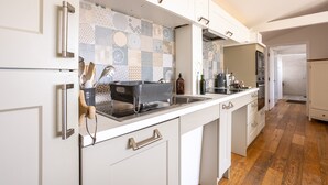 A modern kitchen with white cabinetry, a patterned backsplash, and a wooden floor. - Owain’s Lake View : Pet-Friendly 1‑Bed Lakeside Apartment with Maelog Lake Views | Managed by Angles (Ty Croes)