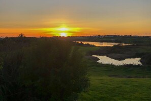 A sunset over a landscape with a body of water and a grassy area.