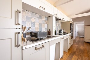 A modern kitchen with white cabinetry, a patterned backsplash, and a wooden floor.