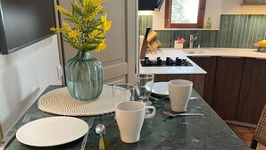 Et spisebord med en vase med gule blomster, en tallerken, bestik og to hvide kopper.