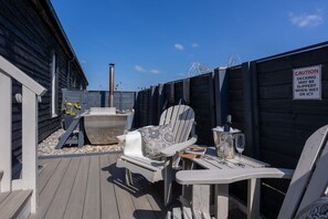 Une terrasse en bois avec des sièges d’extérieur, un barbecue et un panneau d’avertissement.