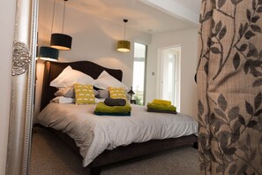 A bedroom with a large bed, a headboard, and a window.