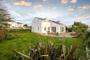 A two-story house with a patio area, a barbecue, and a garden.