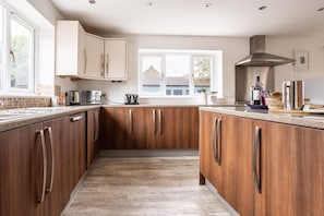 A modern kitchen with wooden cabinets, a stainless steel range hood, and a window providing natural light.
