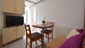 Un espacio habitable compacto con kitchenette, una zona de comedor con dos sillas, un sofá y un radiador.