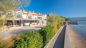 A waterfront building with outdoor seating and a view of the water. - Apartment Tamaris D with Seaview (Čižići)