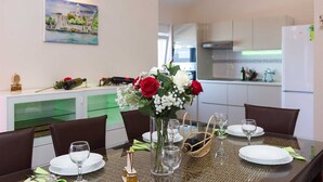 A dining area with a table set for four, a vase with flowers, and a painting on the wall. - Apartment Tamaris D with Seaview (Čižići)