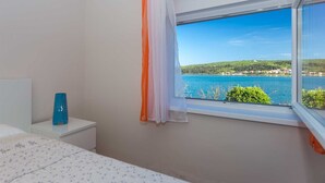 A bedroom with a window offering a view of a lake and hills. - Apartment Tamaris D with Seaview (Čižići)