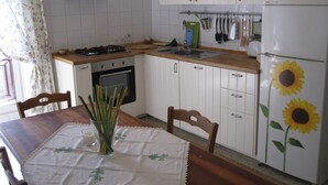 Una cocina con gabinetes blancos, estufa, horno y refrigerador decorado con motivos de girasoles.